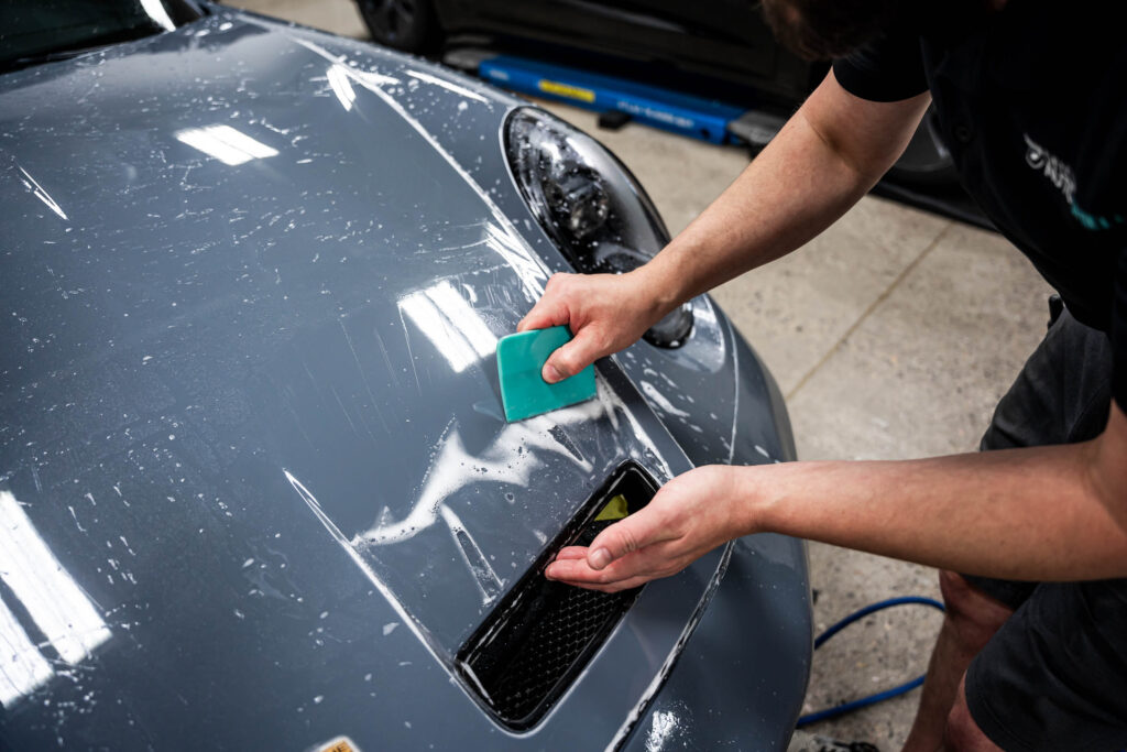 Using a squeegee to install PPF on hood
